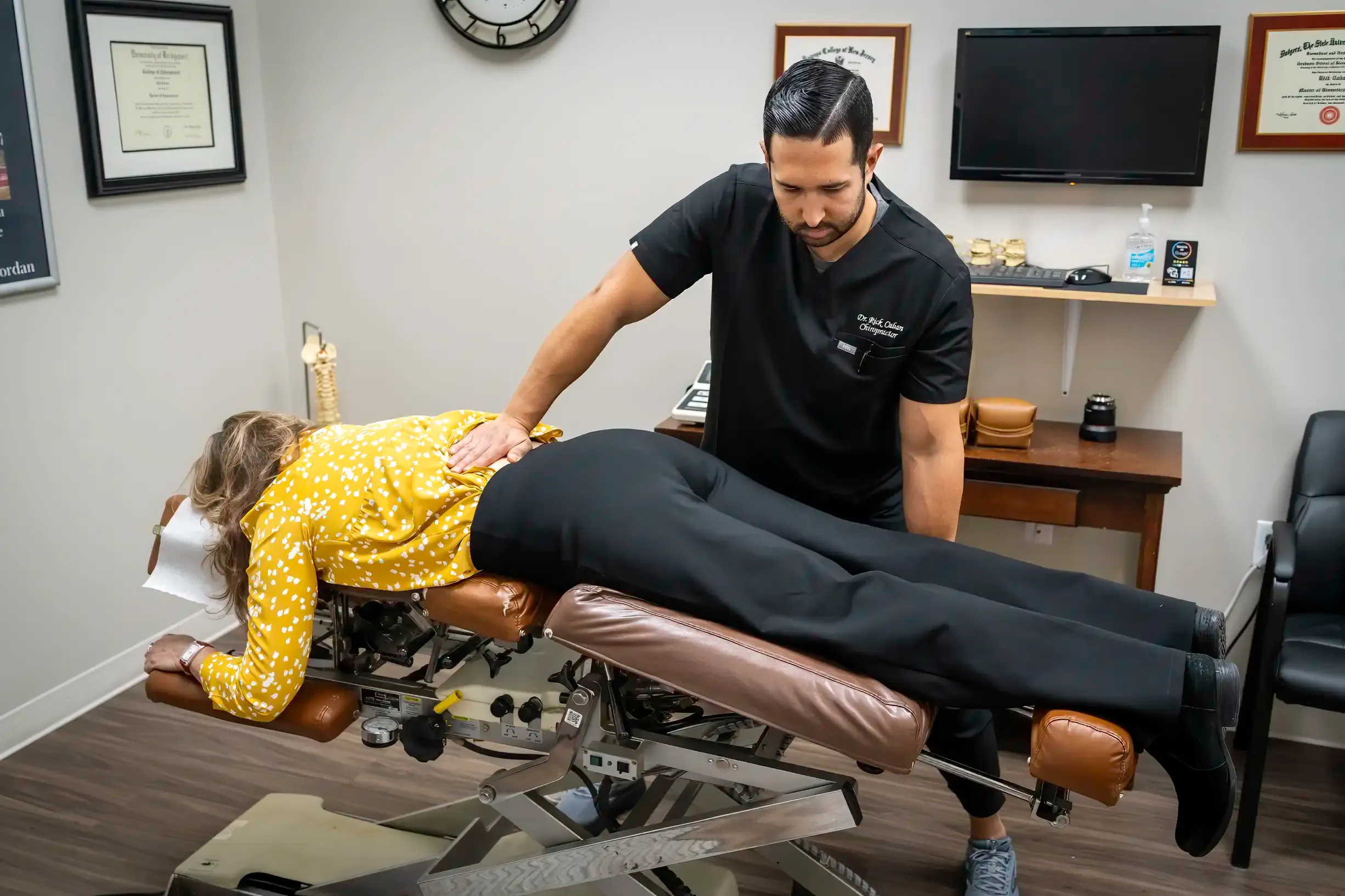 A chiropractor at Limitless Spine & Joint Care adjusts a patient lying face down on an adjustable chiropractic table in a well-lit office — sciatica evaluation in Monmouth County, NJ.