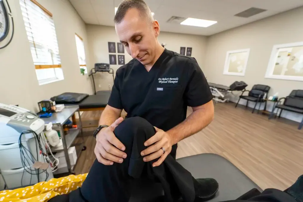 Limitless Healthcare Team from Limitless Spine & Joint Care examines a patient's knee in a bright office setting, providing hands-on physical therapy in Morganville, NJ.