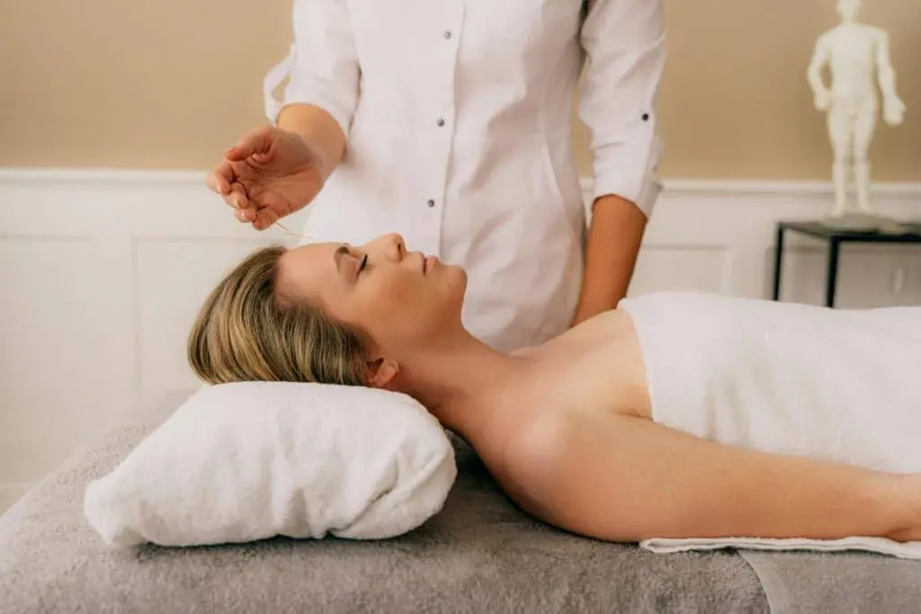 Patient receiving acupuncture on a massage table in a bright, clean treatment room at Limitless Spine & Joint Care in Morganville, NJ.