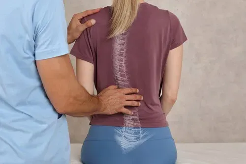 A clinician examines a patient's spine with a translucent vertebral overlay — multidisciplinary spinal stenosis care at Limitless Spine & Joint Care in Morganville, NJ.